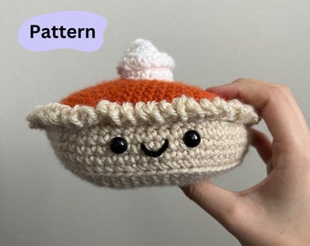 May include: A crocheted pumpkin pie plush toy with a smiling face and whipped cream topping.