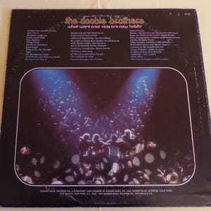 Puede incluir: La contraportada de un disco de vinilo de The Doobie Brothers. El t&iacute;tulo del &aacute;lbum es "What Were Once Vices Are Now Habits". La portada del &aacute;lbum presenta una fotograf&iacute;a en blanco y negro de una multitud de personas en un concierto. Las luces del escenario brillan intensamente sobre la multitud.