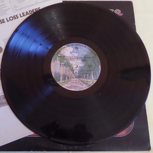 Puede incluir: Disco de vinilo negro con una etiqueta blanca. La etiqueta tiene el texto "What Were Once Vices Are Now Habits" y "The Doobie Brothers" impreso en ella. El disco es de Warner Bros. Records.