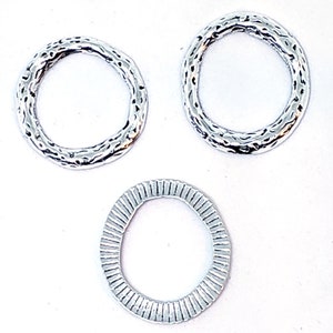 May include: Three silver metal rings with different textures. The rings are all circular and have a smooth, polished finish. The rings are perfect for jewelry making or other craft projects.