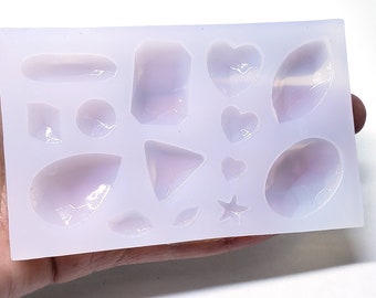 May include: A silicone mold with 13 different shapes for making resin jewelry. The shapes include hearts, stars, ovals, and geometric shapes.