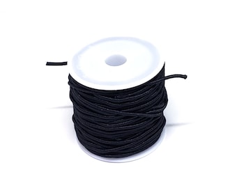 May include: A spool of black elastic cord wound around a white plastic bobbin.