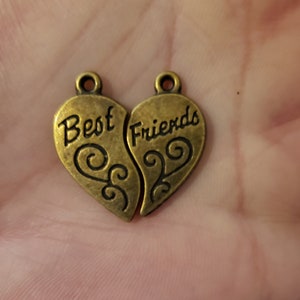 May include: Two gold-tone metal heart charms that fit together. One charm says "Best" and the other says "Friends".