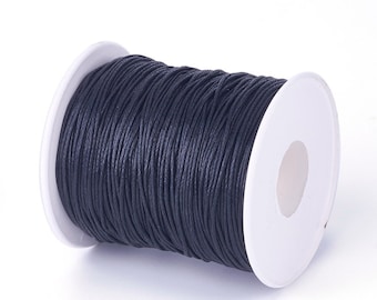 May include: A spool of black waxed cotton cord, wound around a white plastic bobbin.