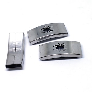 May include: Three silver metal belt buckles, two with a spider cutout design and one plain.