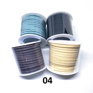 May include: Four spools of suede cord in different colors: teal, black, gray, and cream. The spools are in clear plastic containers with white lids.