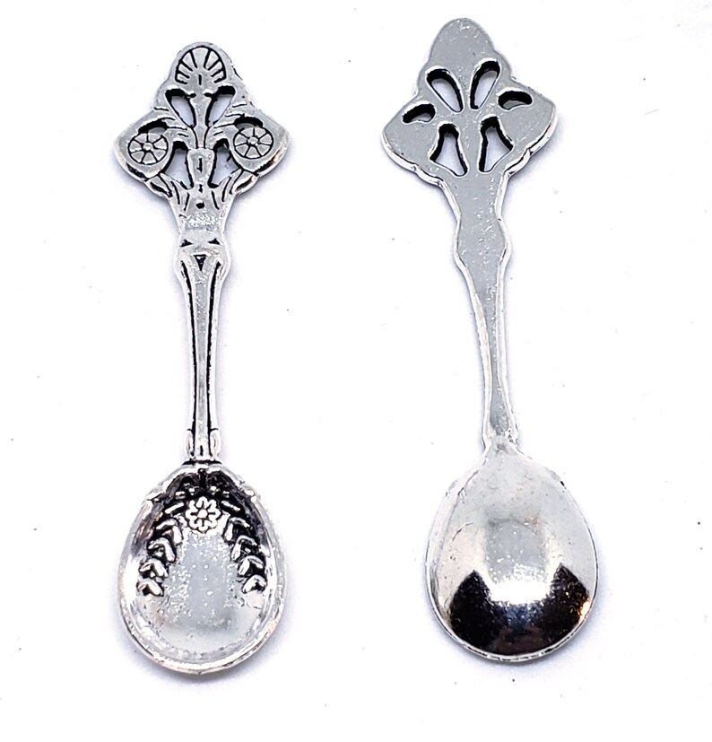 Peut inclure: Deux cuill&egrave;res &agrave; caf&eacute; en argent avec des manches orn&eacute;s et un motif floral. Les cuill&egrave;res ont un bol arrondi et sont parfaites pour servir de petites portions.