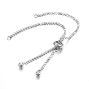 May include: A silver adjustable bracelet with a chain link design and a round bead at the end of each chain. The bracelet has a sliding bead that allows for a custom fit.