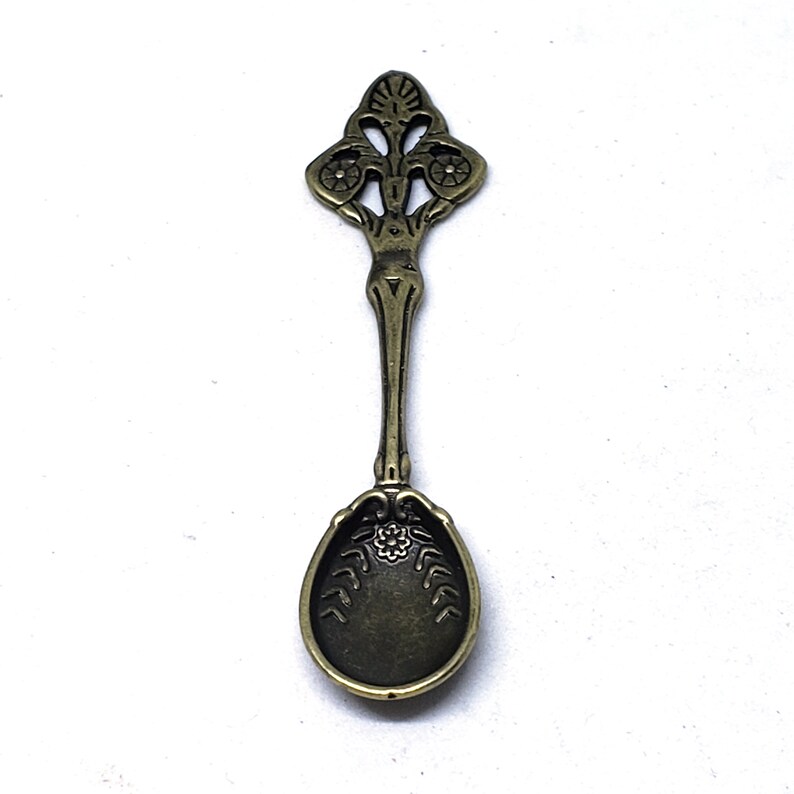Peut inclure: Une petite cuill&egrave;re orn&eacute;e de bronze avec un manche d&eacute;coratif et un bol arrondi. Le manche pr&eacute;sente un motif floral avec des d&eacute;tails complexes.