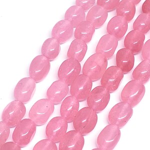 May include: Close-up of strands of polished, oval-shaped rose quartz beads. The beads are a soft pink color and have a smooth, glossy surface. The beads are strung together, creating a beautiful and natural look. Ideal for jewelry making.