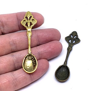 Peut inclure: Deux cuill&egrave;res en m&eacute;tal orn&eacute;es d'un motif floral d&eacute;coratif. La cuill&egrave;re de gauche est dor&eacute;e et celle de droite est en bronze.