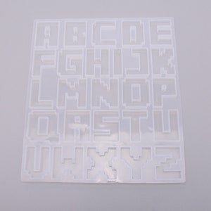 May include: White plastic alphabet mold with raised letters A through Z.