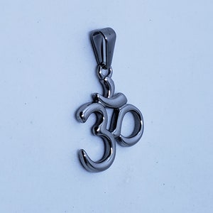 May include: A silver Om symbol pendant with a loop for attaching to a chain or cord.