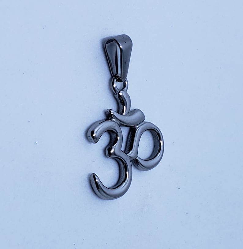 May include: A silver Om symbol pendant with a loop for attaching to a chain or cord.