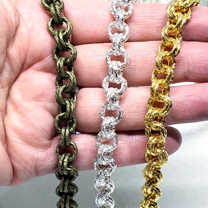 Puede incluir: Tres cadenas de eslabones metálicos en diferentes colores: verde oliva, plata y oro. Las cadenas están hechas de pequeños eslabones redondos que se entrelazan.
