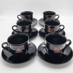 Puede incluir: Juego de seis tazas de té negras y platillos con un diseño geométrico en rojo y blanco.