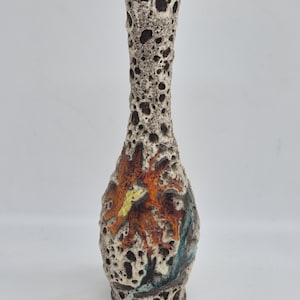 Peut inclure: Un vase en céramique haut et élancé présentant une surface fortement texturée et poreuse dans des tons crème et brun foncé. Le corps affiche un motif abstrait en relief avec des accents orange, jaunes et bleu sarcelle intégrés à l'émail.