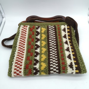 May include: A green, brown, white, red, and yellow crocheted handbag with a brown plastic handle.