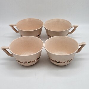 May include: Set of four cream-colored ceramic teacups with a brown, green, and white geometric pattern around the rim.
