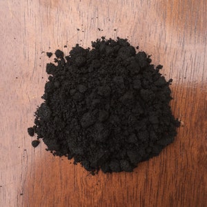 Puede incluir: Primer plano de un mont&oacute;n de tierra negra sobre una superficie de madera.