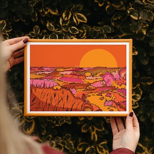 May include: A framed illustration of a sunset over a landscape with rolling hills and fields in shades of orange, pink, and yellow.