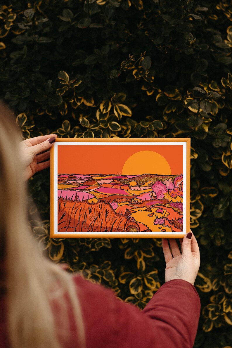 May include: A framed illustration of a sunset over a landscape with rolling hills and fields in shades of orange, pink, and yellow.