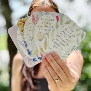 May include: A set of rectangular cards with rounded corners, featuring watercolor floral illustrations and printed text. The visible text includes 'Before I formed you in the womb I knew you' and 'Fear not, for I am with you; be not dismayed'.