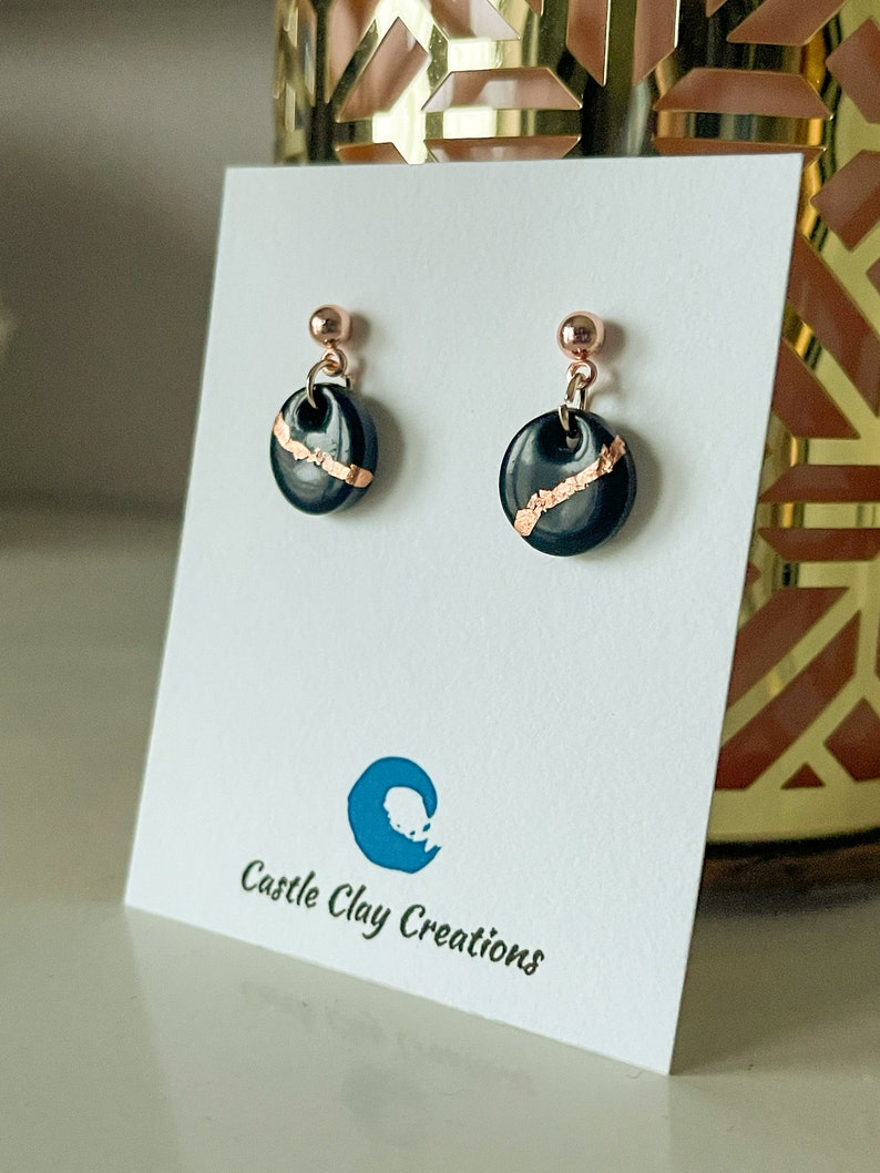 Handmade polymer clay circle earrings black with rose gold leaf detail.