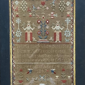 May include: An antique sampler with a brown background, featuring a floral design, two figures, and a verse of text that reads "Te little flock whom Jesus feed Dismiss, your anxious cares & look to the Shepherd, for yours Anb smile swe) Your fears are less Te little flock I've fed for 2 years 1847".