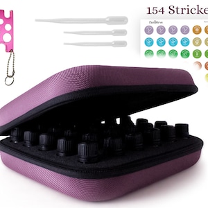 Peut inclure: Un étui de transport pour huiles essentielles de couleur mauve, avec des flacons noirs à l'intérieur. L'étui est ouvert, révélant les flacons. Un outil rose et trois compte-gouttes transparents sont également visibles. L'image comprend également une feuille d'autocollants avec le texte "154 Strickers!"