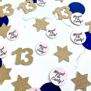 May include: Gold glitter confetti with the number 13 and pink circles with the text "Mazel Tov Carly!" on a white background.