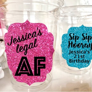 May include: Two clear plastic cups with glitter stickers. The pink sticker says "Jessica's legal AF". The blue sticker says "Sip Sip Hooray Jessica's 21st Birthday".