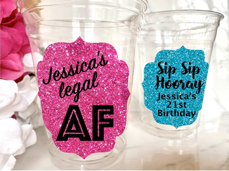 May include: Two clear plastic cups with glitter stickers. The pink sticker says "Jessica's legal AF". The blue sticker says "Sip Sip Hooray Jessica's 21st Birthday".