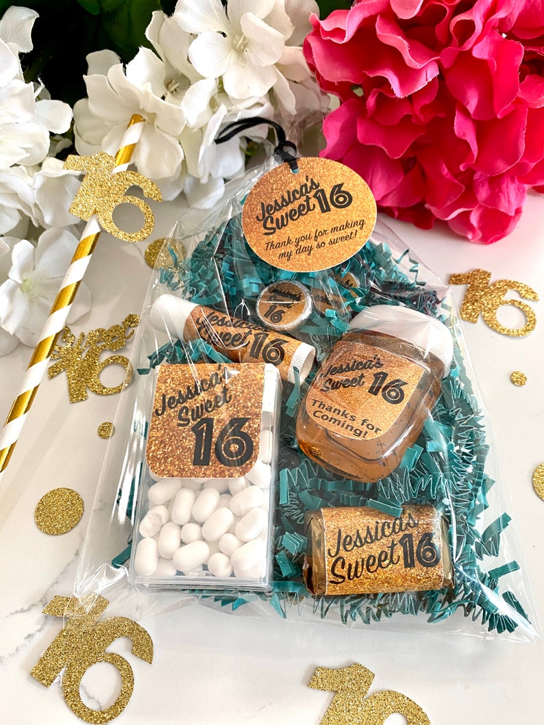 May include: A clear plastic bag filled with party favours for a Sweet 16 birthday party. The bag contains a small bottle of hand sanitiser, a small container of mints, a chocolate bar, and a lip balm. All of the items have gold glitter and the text "Jessica's Sweet 16" on them.