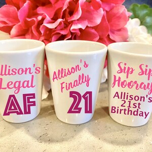 May include: Three white shot glasses with pink lettering. The first glass says "Allison's Legal AF". The second glass says "Allison's Finally 21". The third glass says "Sip Sip Hooray! Allison's 21st Birthday".