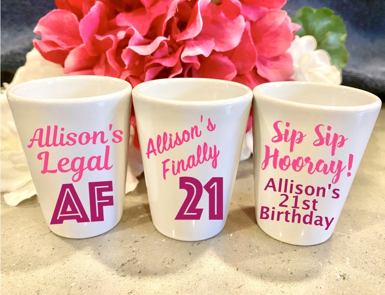 May include: Three white shot glasses with pink lettering. The first glass says "Allison's Legal AF". The second glass says "Allison's Finally 21". The third glass says "Sip Sip Hooray! Allison's 21st Birthday".