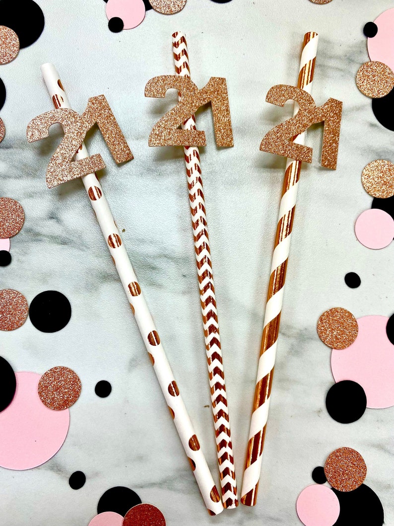 May include: Three gold glitter straws with the number 21 on each straw. The straws have different patterns: white with black polka dots, white with black chevron, and white with red stripes.