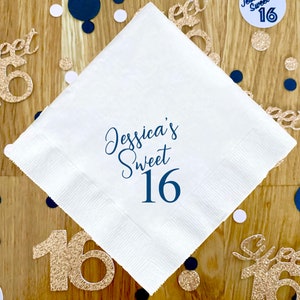 May include: White paper napkin with blue text that reads "Jessica's Sweet 16". The napkin is surrounded by gold and blue confetti.
