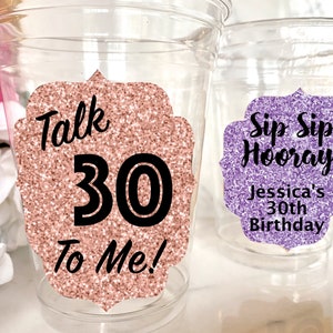 May include: Two clear plastic cups with glitter-covered paper stickers. The pink cup has the text "Talk 30 To Me!" and the purple cup has the text "Sip Sip Hooray! Jessica's 30th Birthday".