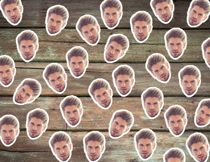 May include: A wood background with multiple white stickers of a man's face. The man has short brown hair and is looking directly at the camera.
