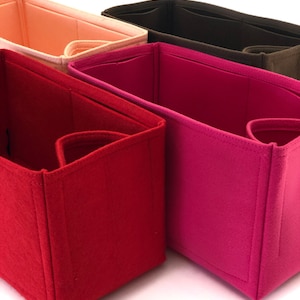 May include: Four felt bag organizers in different colors: red, pink, brown, and peach. The organizers are folded and stacked on top of each other.
