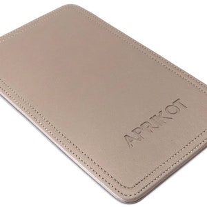 May include: A beige leather mouse pad with a stitched border and the word "APRIKOT" embossed in the center.