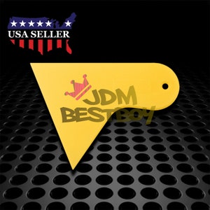 May include: Yellow plastic tool with a rounded edge and a hole in the top. The tool has a crown and the text "JDM BESTBOY" printed on it.