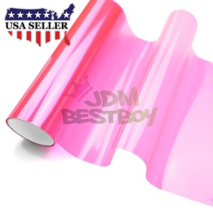 May include: A roll of pink car wrap vinyl film. The film is translucent and has a glossy finish. The text "JDM BESTBOY" is visible on the film.