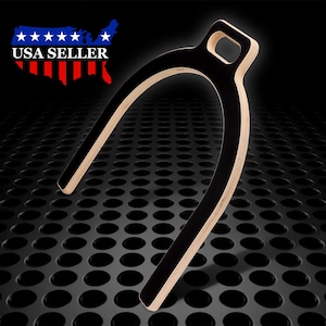 May include: A black wooden horseshoe-shaped hanger with a cutout handle. The hanger is on a black background with a grid pattern.