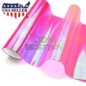 May include: A roll of iridescent pink vinyl film with a holographic finish. The film is rolled up and has a white core. The film is a popular choice for car wraps and other decorative projects.