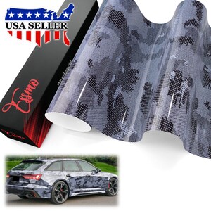 May include: A roll of adhesive vinyl wrap featuring a gray, black, and white digital camouflage pattern with a textured dot matrix finish. The product is displayed next to a black box labeled Essmo and a photo of a station wagon with the same wrap.