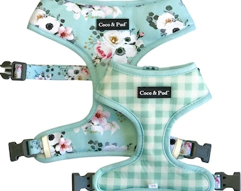 May include: Two dog harnesses in a light blue color. One harness has a floral pattern and the other has a white and light blue gingham pattern. Both harnesses have the text "Coco & Pud" on them.