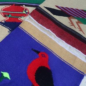 Peut inclure: Gros plan sur trois pièces textiles tissées avec des motifs d'oiseaux et géométriques. Les textiles présentent des couleurs vives, notamment le bleu, le rouge, le vert et le beige. Les motifs d'oiseaux sont proéminents.