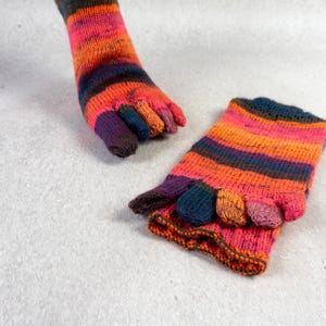 May include: A pair of colourful toe socks with a striped pattern in shades of orange, pink, purple, and brown. The socks are made of a soft, knitted fabric.